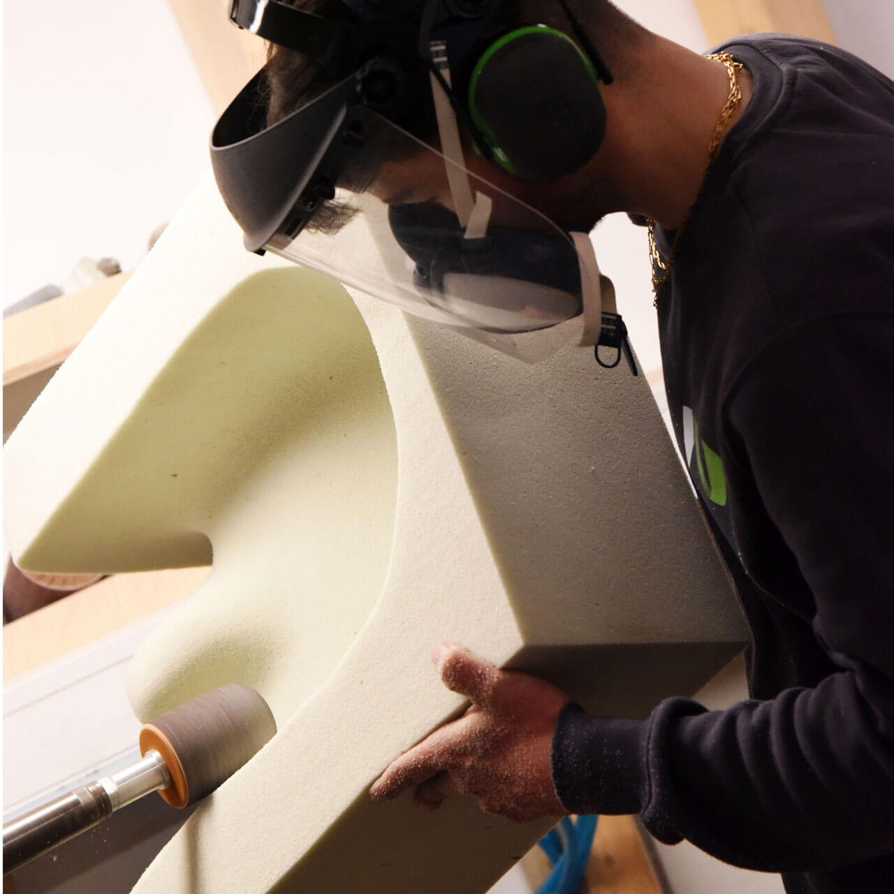 Ein Orthopädietechniker arbeitet in der Werkstatt und bearbeitet einen Sitz aus Schaumstoff